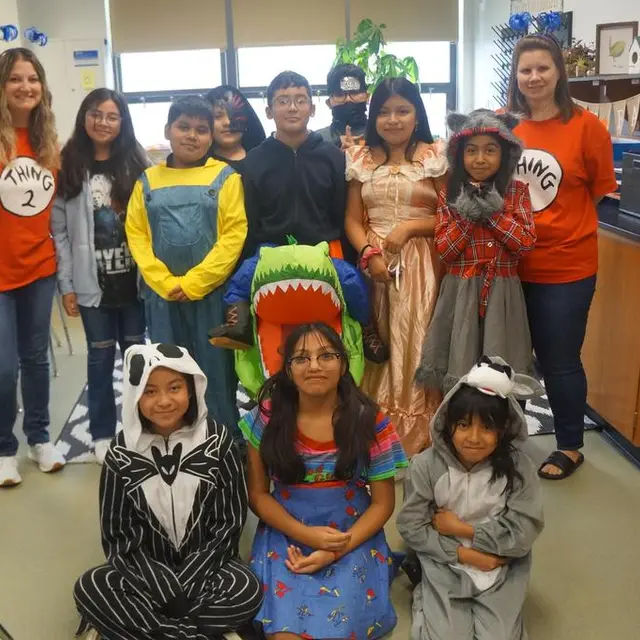 A class and two teachers in Thing 1 and Thing 2 shirts, with scholars in costume in front