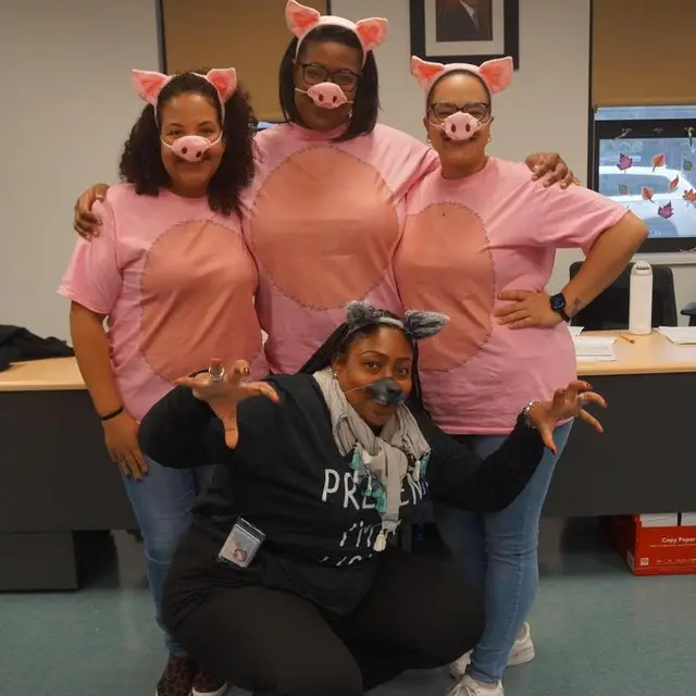 Three staff members dressed as pigs and one as a wolf