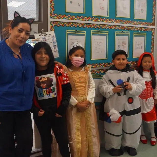 A teacher with scholars dressed as an astronaut, a princess and other characters