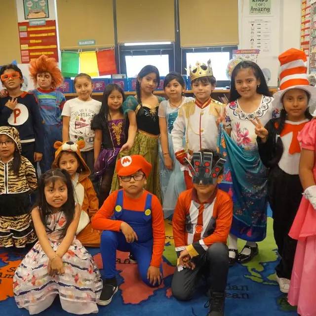 A class in costume gathered on the classroom rug