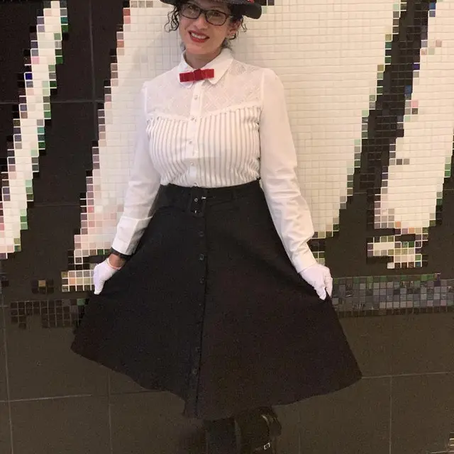 A staff member dressed as a nanny in a white blouse, black skirt and bow tie