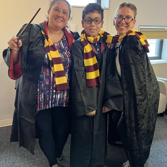 Two staff members and a scholar dressed as wizards in striped scarves