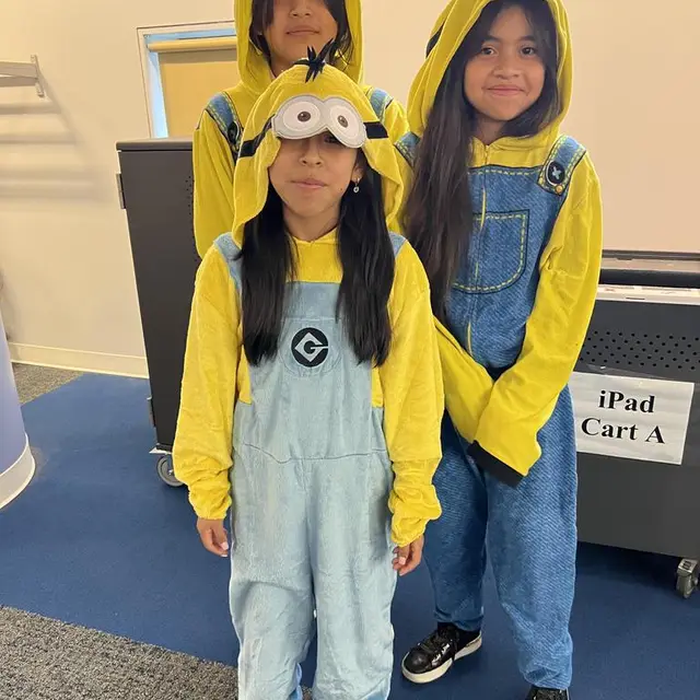 Two scholars dressed as yellow minions in blue overalls