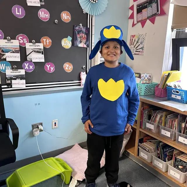 A scholar in a blue costume hat and shirt in the classroom